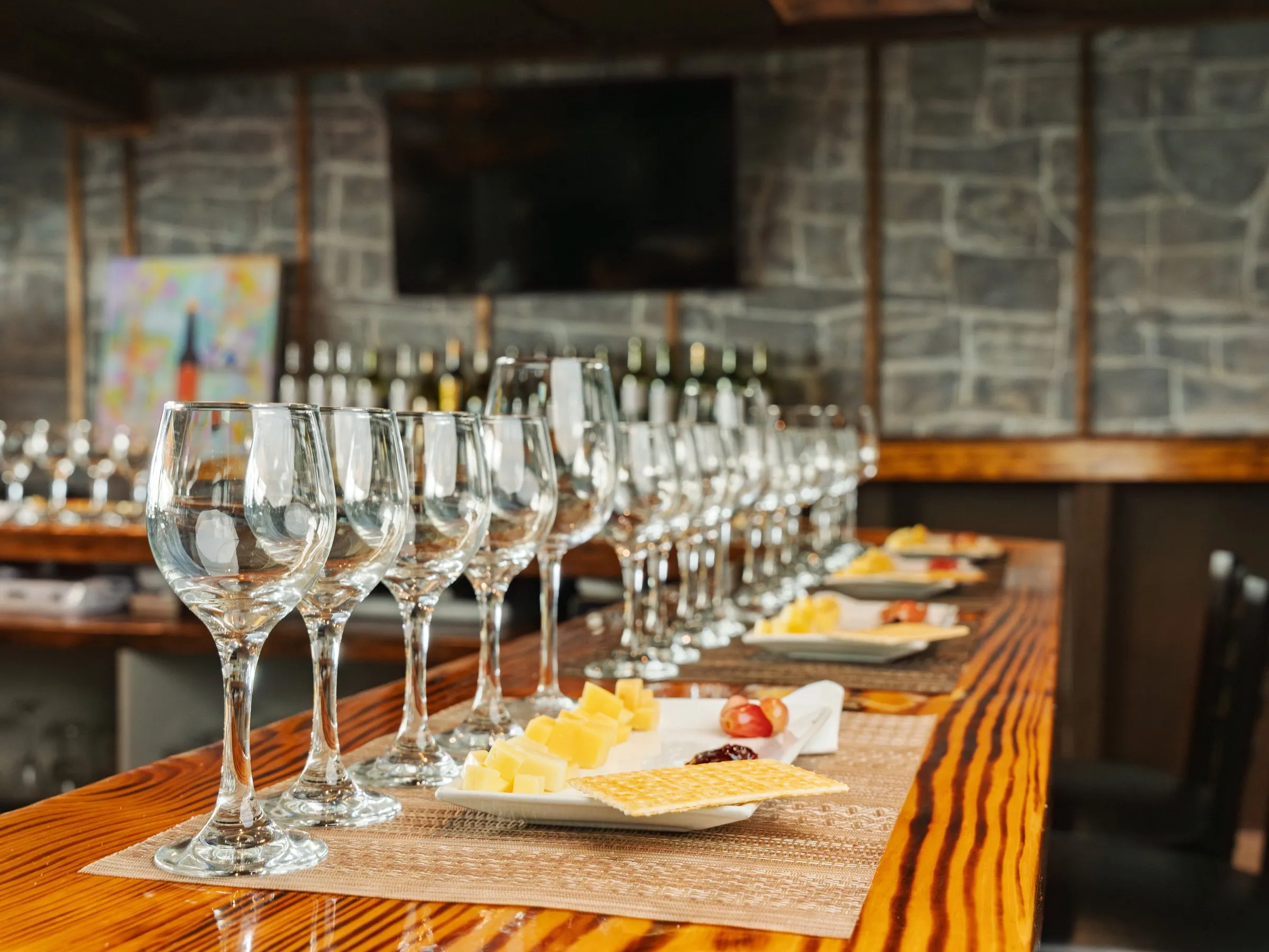 Wine glasses and cheese plates set out along a long tasting table